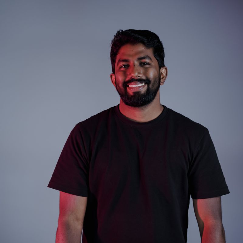 Shabeeb Nattukal leaning on a desk, smiling